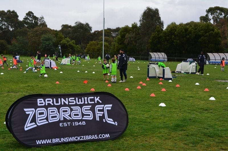Vivir en Australia equipo de fútbol entrenando en el campo de césped y un entrenador que los mira